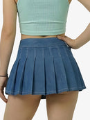 Person wearing a blue pleated skirt and light green crop top on a white background