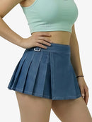 Person wearing a light green crop top and blue pleated skirt on a white background