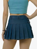 Person wearing a blue pleated skirt and crop top on a white background