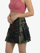 Person wearing a black and green plaid kilt with pink top on a white background