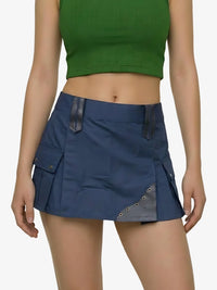 Person wearing a blue skirt with a green top on a plain background