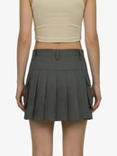 Person wearing a gray pleated skirt with pockets on a white background