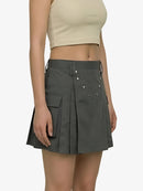 Person wearing a gray pleated skirt with button details on a white background