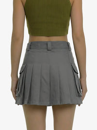 Person wearing a green crop top and gray pleated skirt on a white background