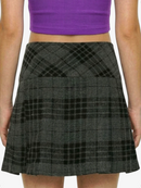 Person wearing a gray plaid skirt and purple top