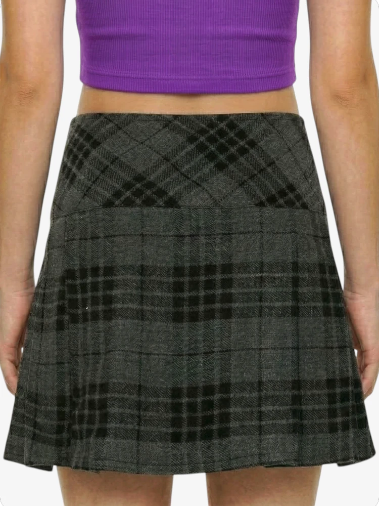 Person wearing a gray plaid skirt and purple top