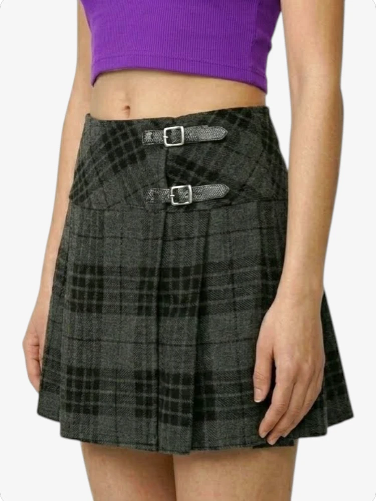 Person wearing a black plaid skirt with silver buckles on a white background