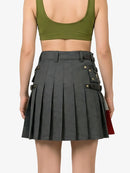 Person wearing a green crop top and gray pleated skirt on a plain background