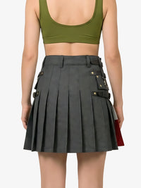 Person wearing a green crop top and gray pleated skirt on a plain background