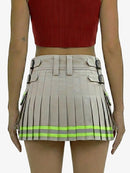 Person wearing a beige pleated skirt with reflective green stripes and a red top on a white background
