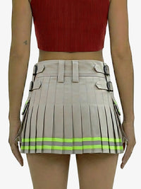 Person wearing a beige pleated skirt with reflective green stripes and a red top on a white background