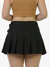 Person wearing a black pleated skirt and brown top on a plain background