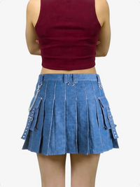 Person wearing a blue pleated skirt with chain details on a white background