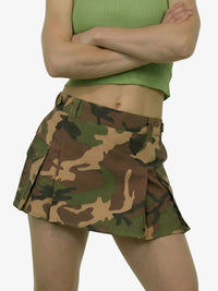 Person wearing a green top and camouflage skirt on a white background