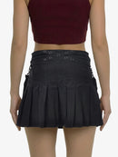 Black pleated skirt with eyelet details worn by a person on a white background