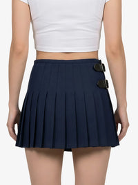 Navy pleated skirt with black buckles worn by a person on a white background