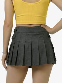 Person wearing a yellow crop top and black pleated skirt on a white background