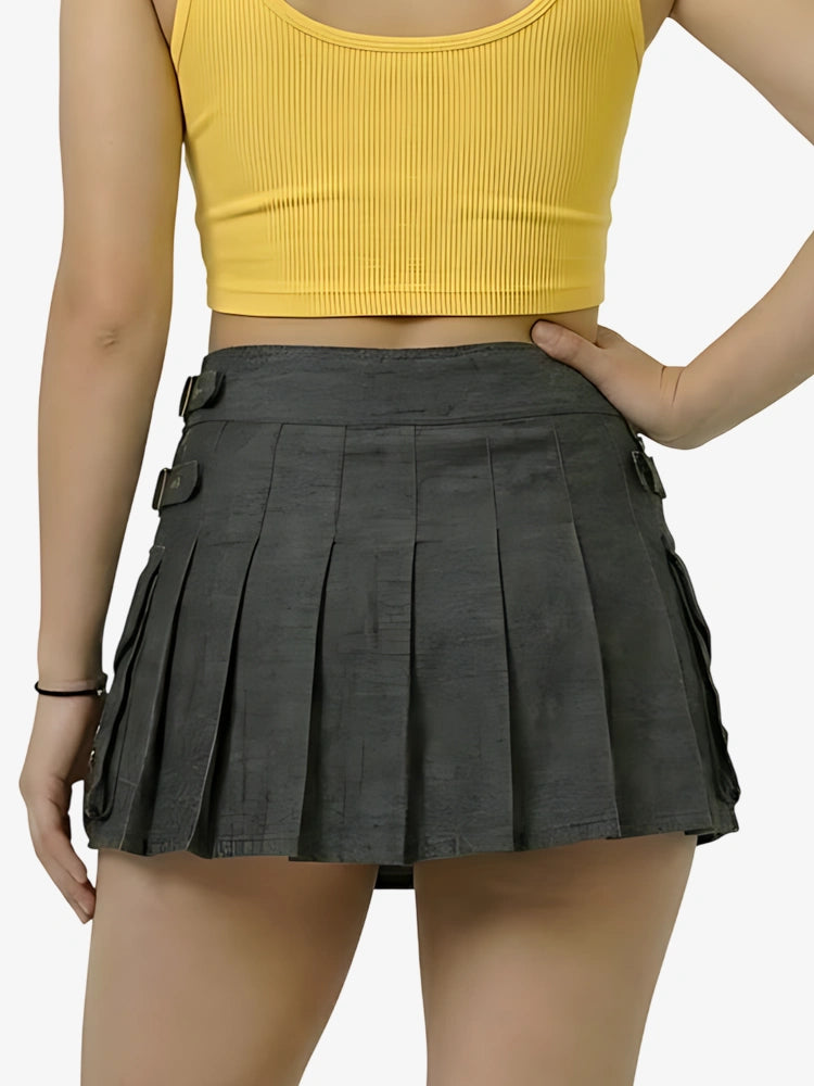 Person wearing a yellow crop top and black pleated skirt on a white background