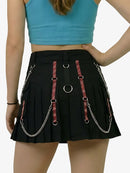 Black pleated skirt with red and silver chains worn by a person on a white background