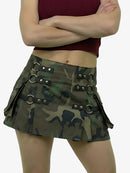 Person wearing a camouflage skirt with metal accents on a plain background