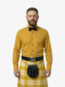 Man wearing a yellow shirt, bow tie, and kilt on a white background