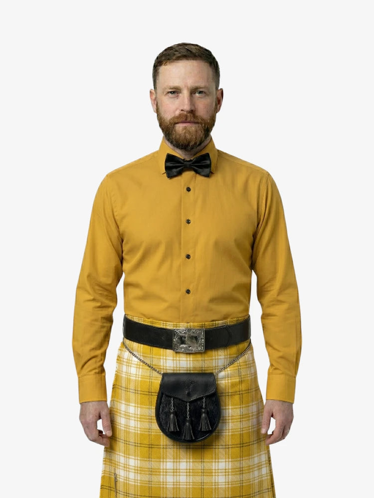 Man wearing a yellow shirt, bow tie, and kilt on a white background