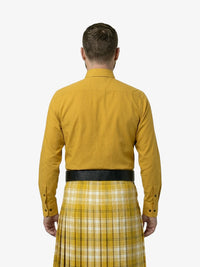 Man wearing a mustard yellow shirt and plaid kilt on a white background