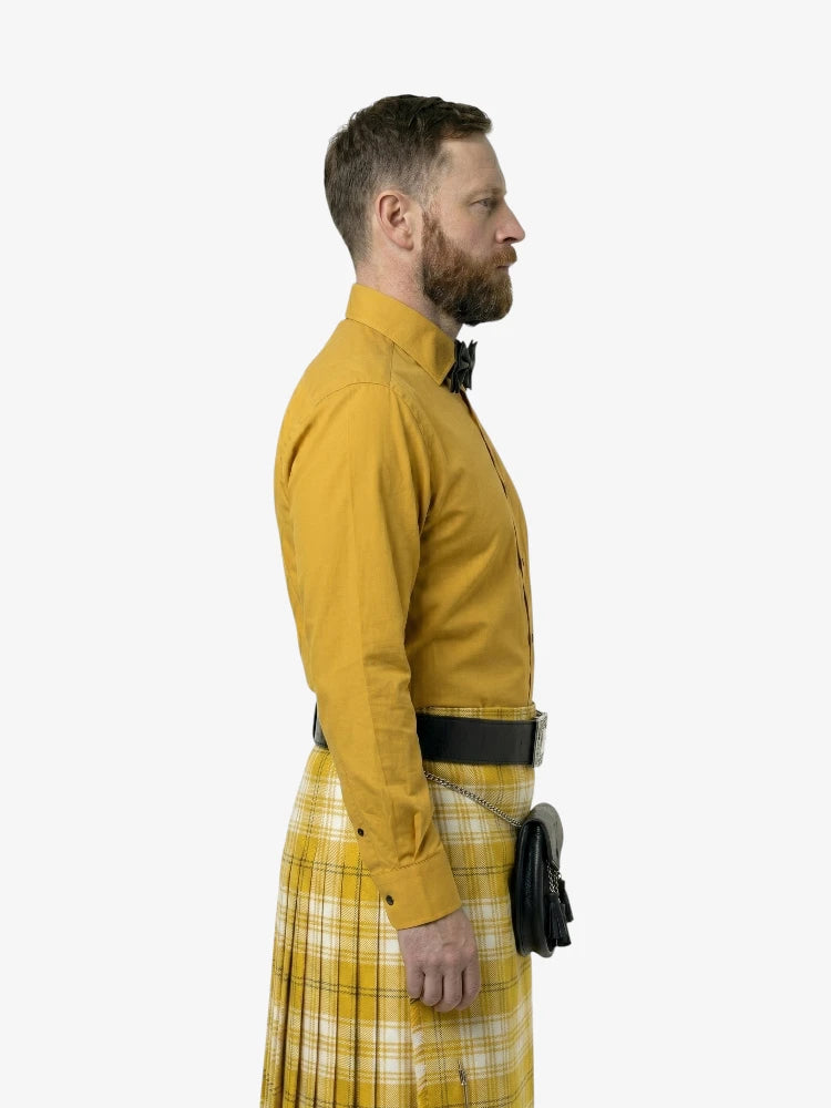 Man wearing a yellow shirt and plaid kilt on a white background