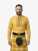 Man wearing a yellow shirt with black embroidery and a plaid kilt on a white background