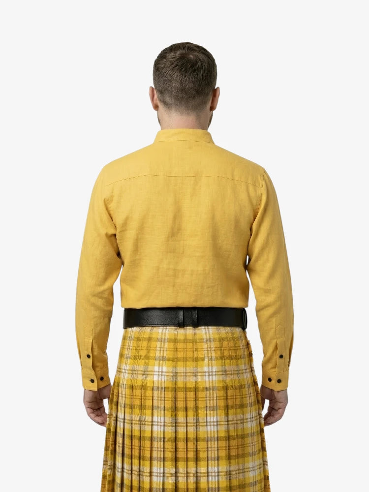 Man wearing a yellow shirt and plaid kilt on a white background