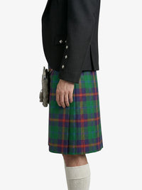 Person wearing a black jacket and green plaid kilt on a white background